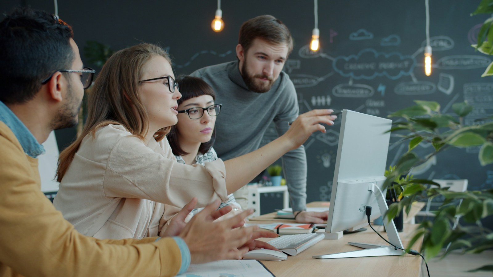 Colleagues collaborating around a computer in an open-plan office